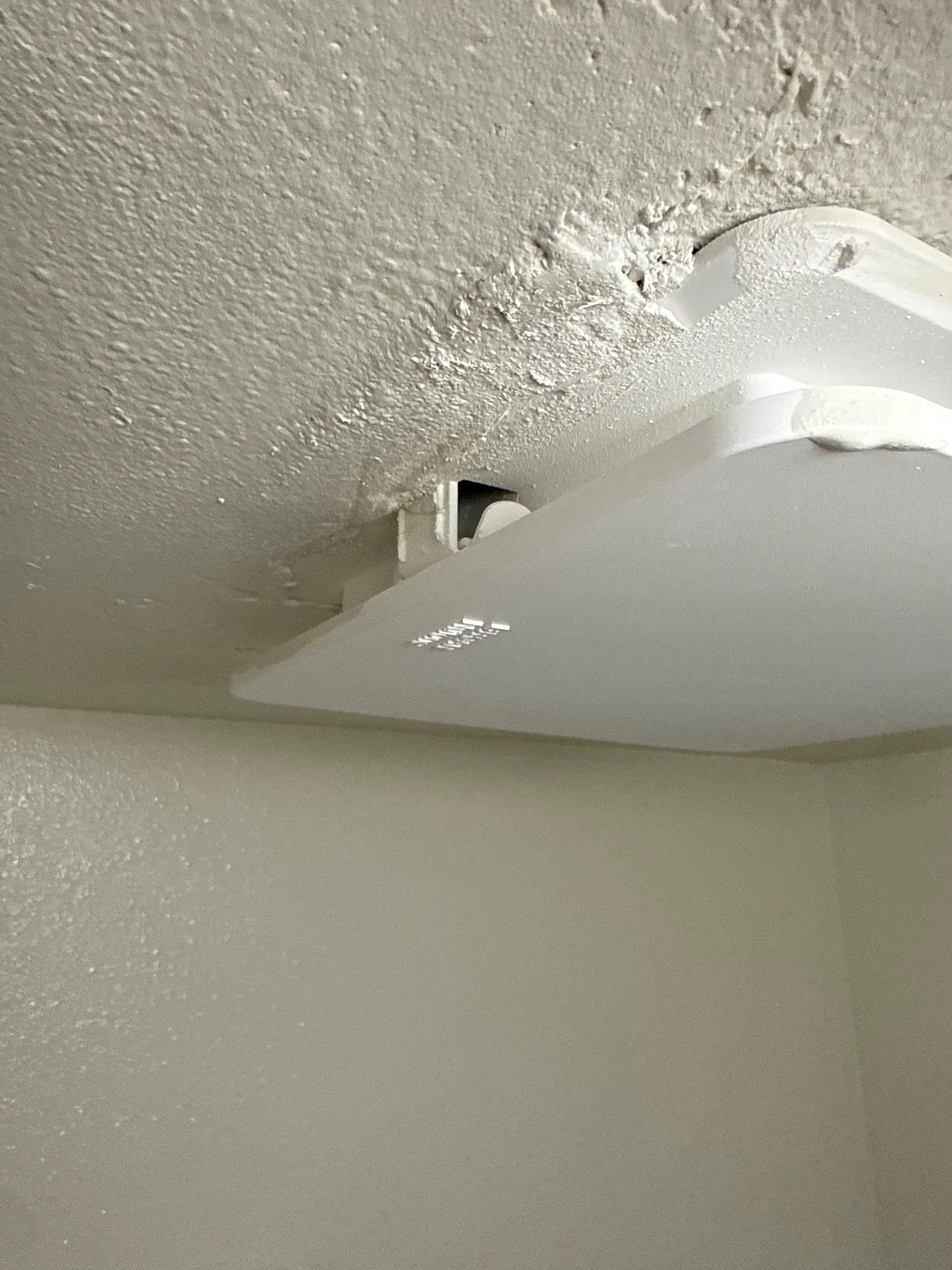 White PVC drain pipe mounted to drywall with support bracket and proper installation