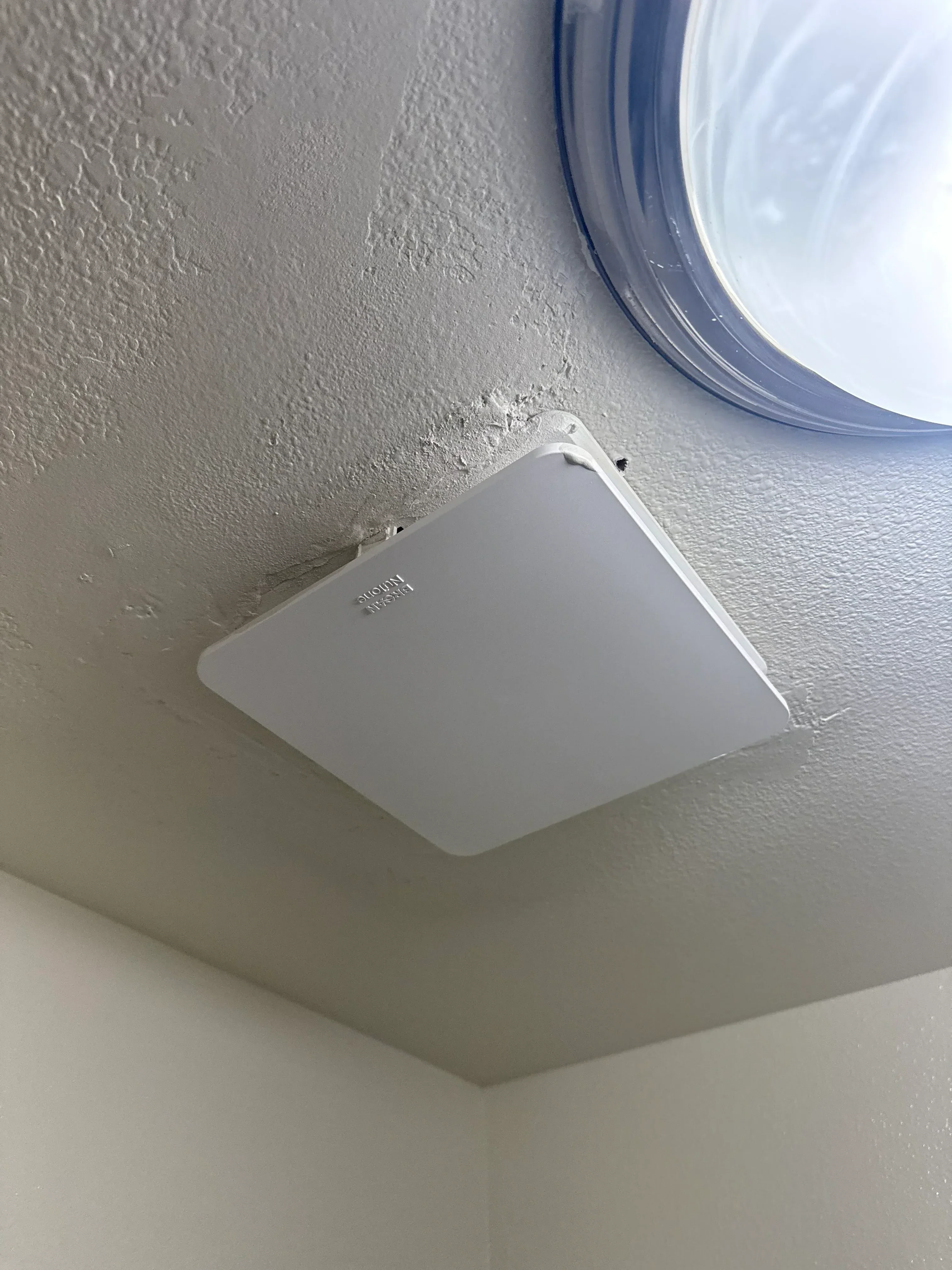 White utility access box mounted on drywall with textured finish and plumbing connections