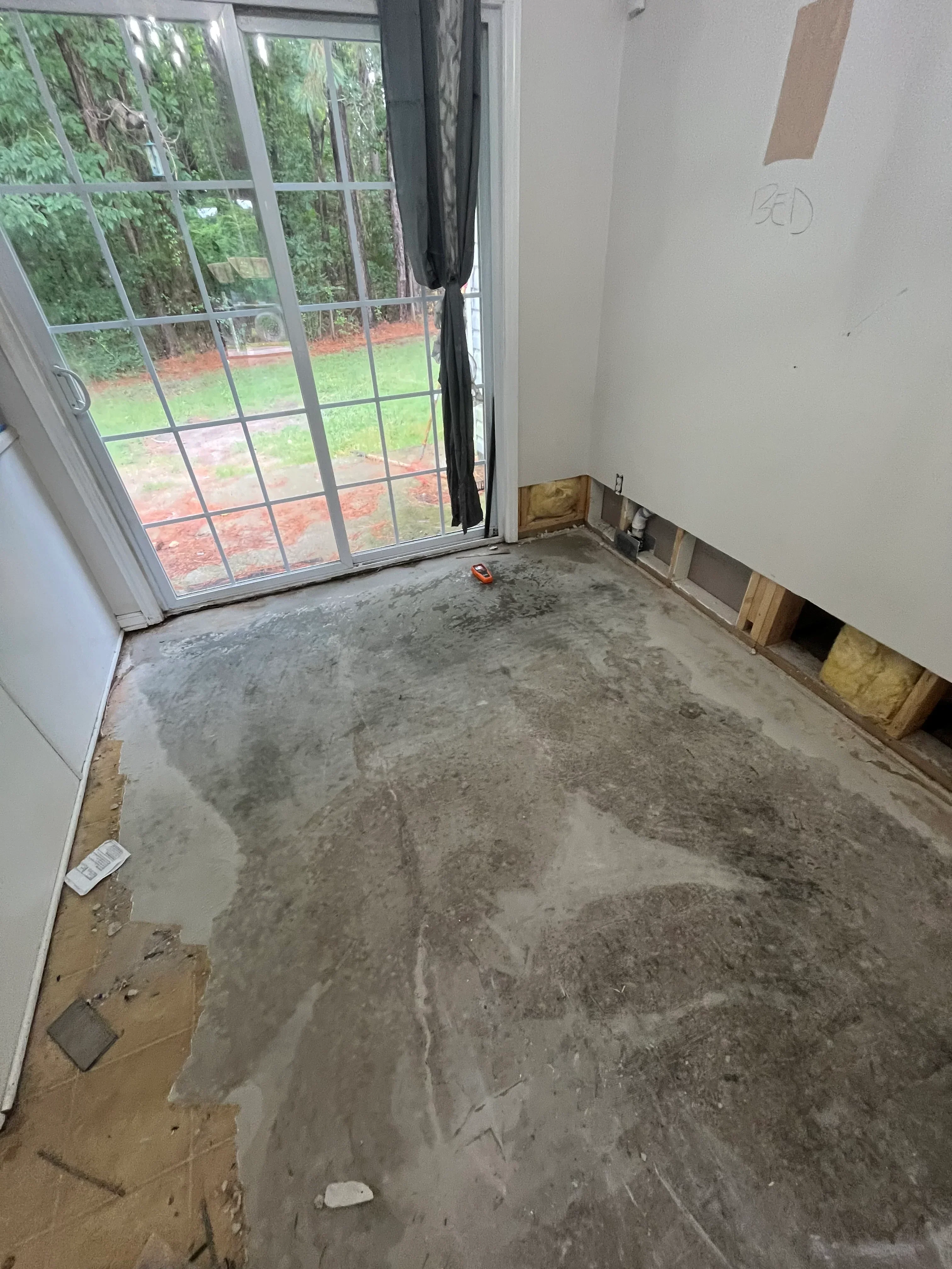 Unfinished basement with exposed concrete wall, wooden framing, and basement window