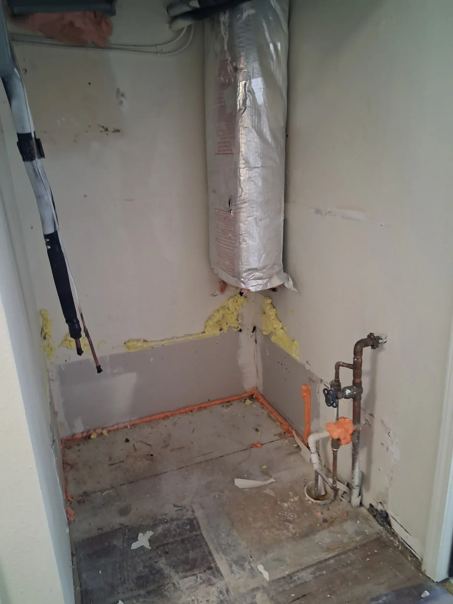 Bathroom rough-in with copper supply lines, drain pipes, and fixture stubs during construction