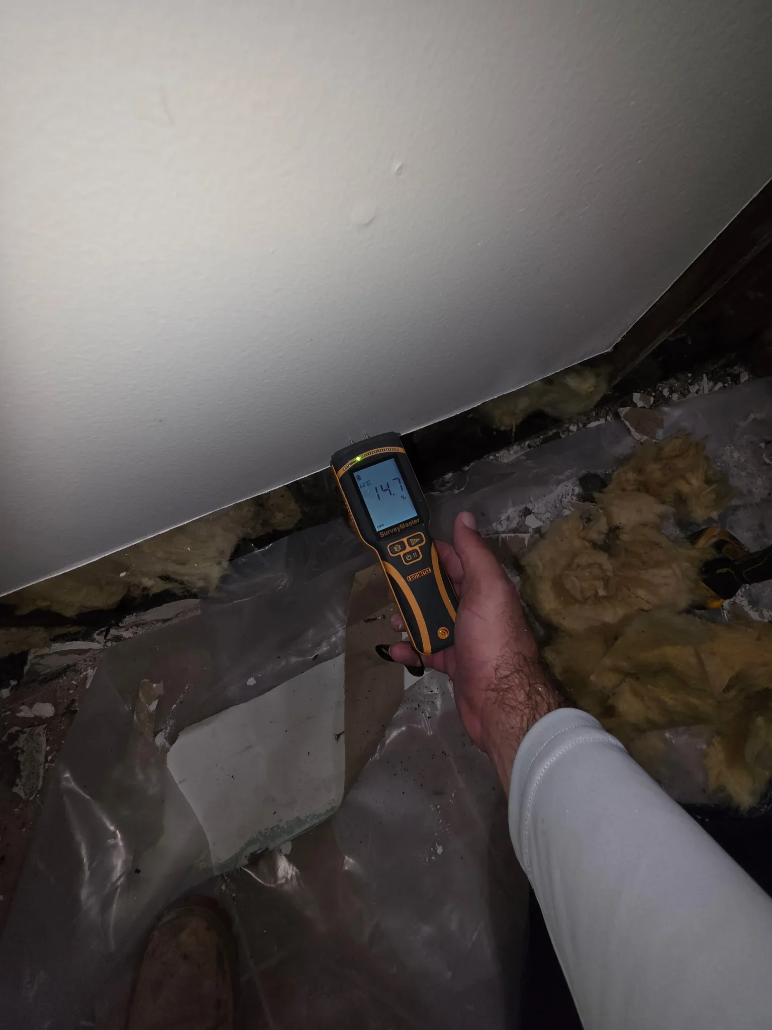 Moisture meter reading 74% on wet fiberglass insulation in attic space with water damage