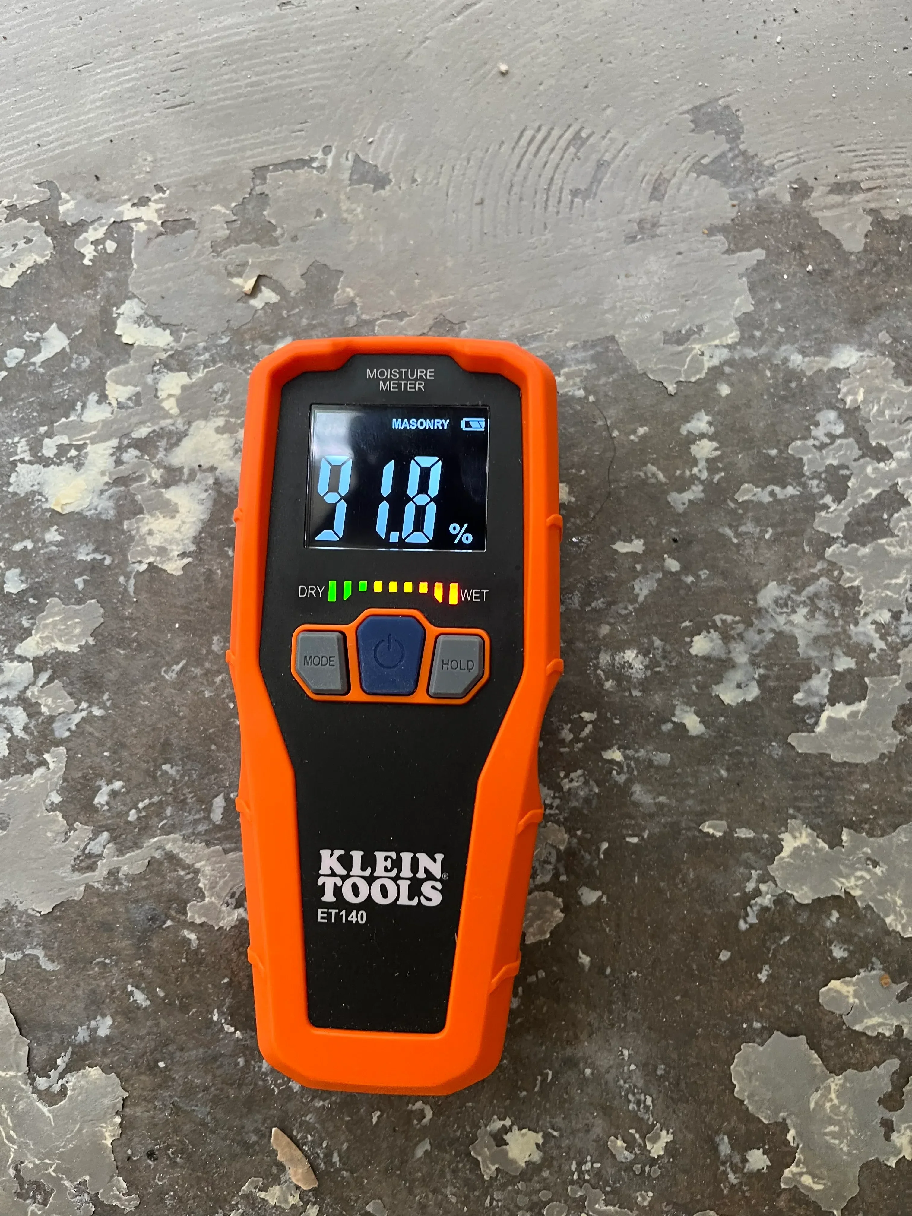 Moisture meter on damaged drywall with peeling paint and plaster deterioration